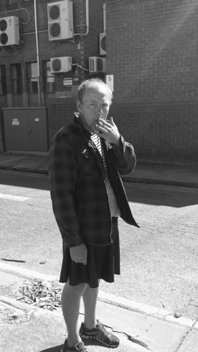 Portrait of a men with a cigarette standing at a street corner.