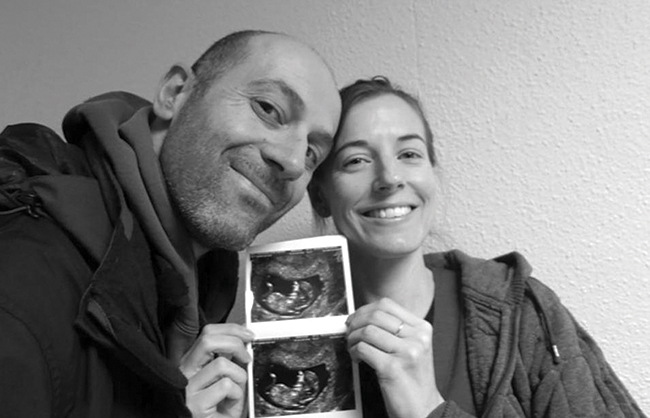 Smiling couple holding a print out of ultrasound images.
