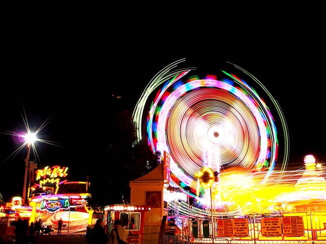 Lit up rides in motion in a fun park at night