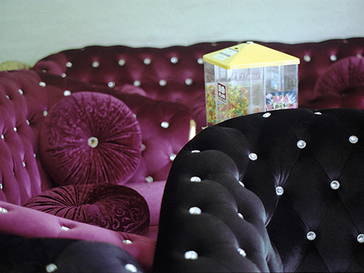Image of purple and black couches with glass stoned and a sweets dispenser between them