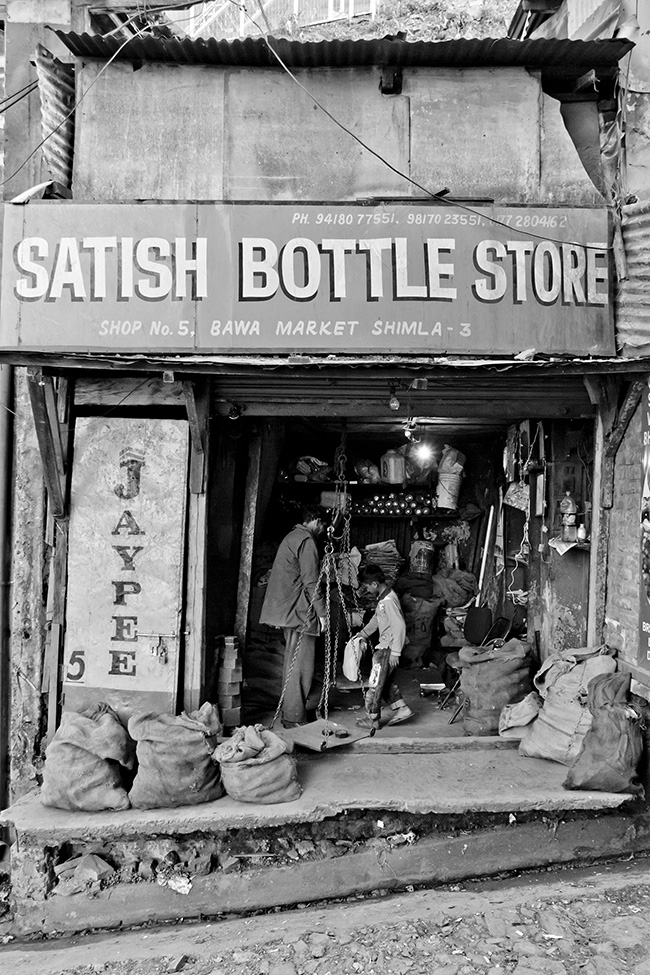 Black and white image of a store front with several bags of goods on display